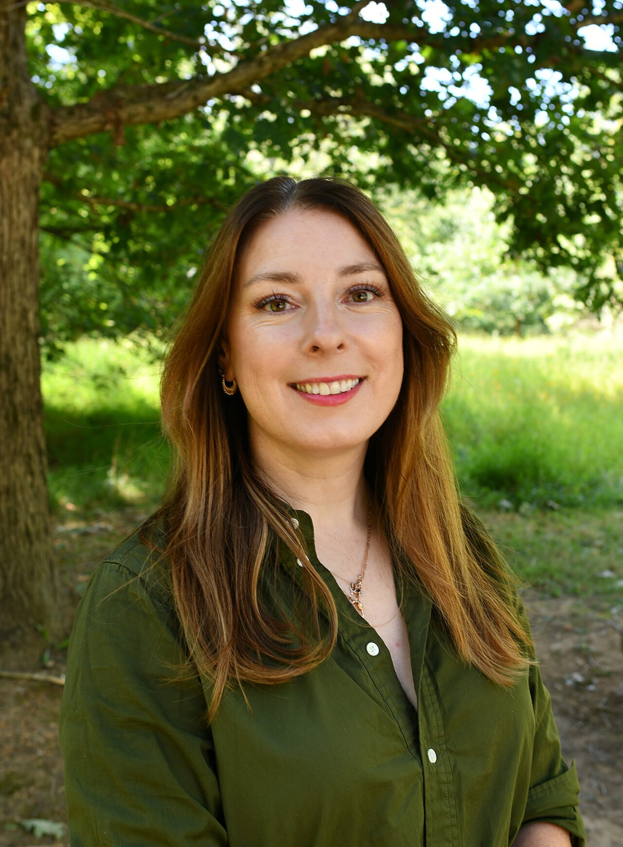 A woman with a green shirt on smiles at the camera