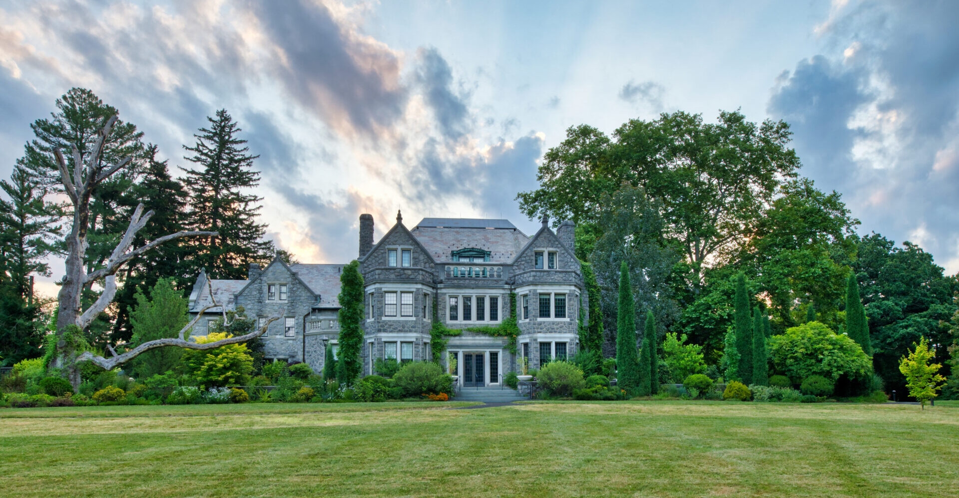 Photo by David Korbonits
 - The Main House at Stoneleigh with a tree sculpture near sunrise in summer. 
