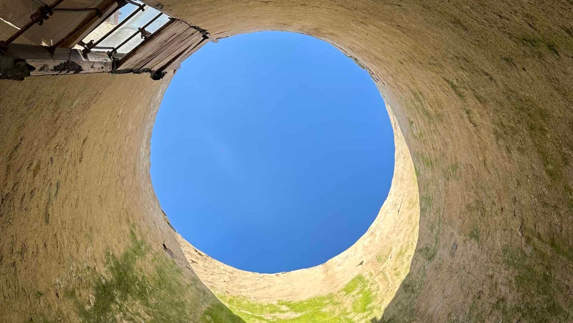 daytime sky showing through a circular opening in a silo that is temporarily without a roof