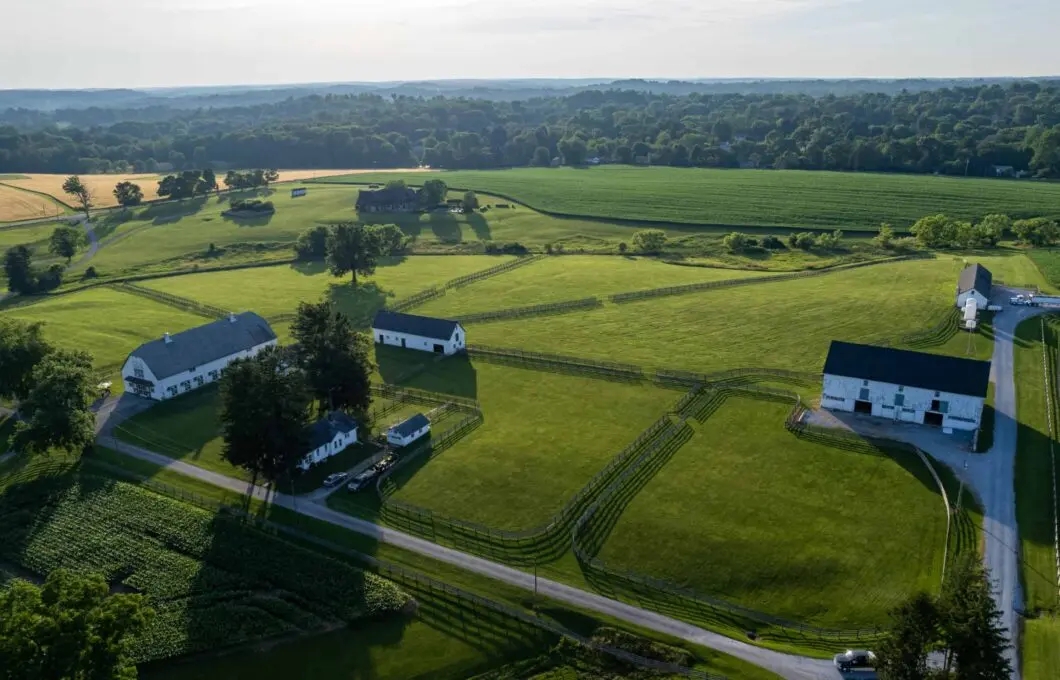 Drone photo of the green landscape of a sprawling farm with white farmhouses.
