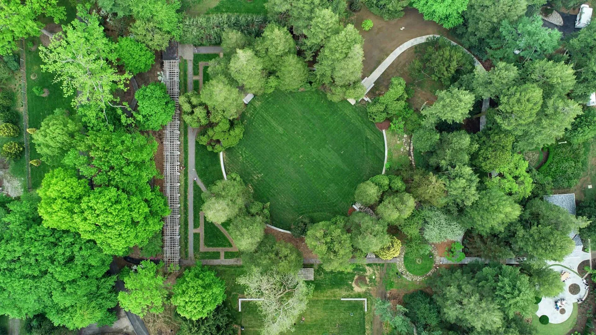 aerial photograph of a landscape including a green circle surrounded by leafy green trees