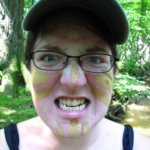 Molly Smyrl makes a face at the camera while wearing mud paint and a ball cap.