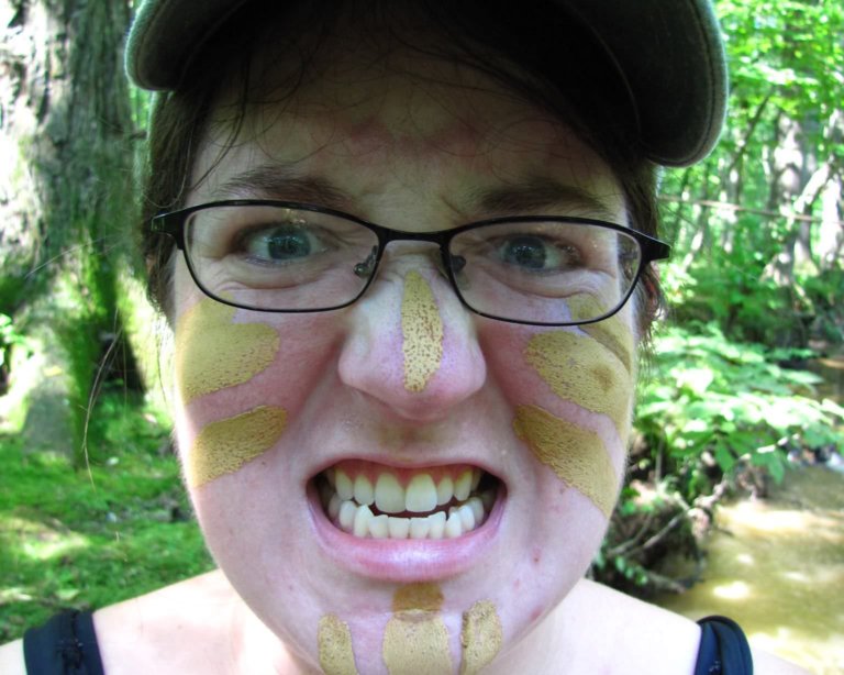 Molly Smyrl makes a face at the camera while wearing mud paint and a ball cap.
