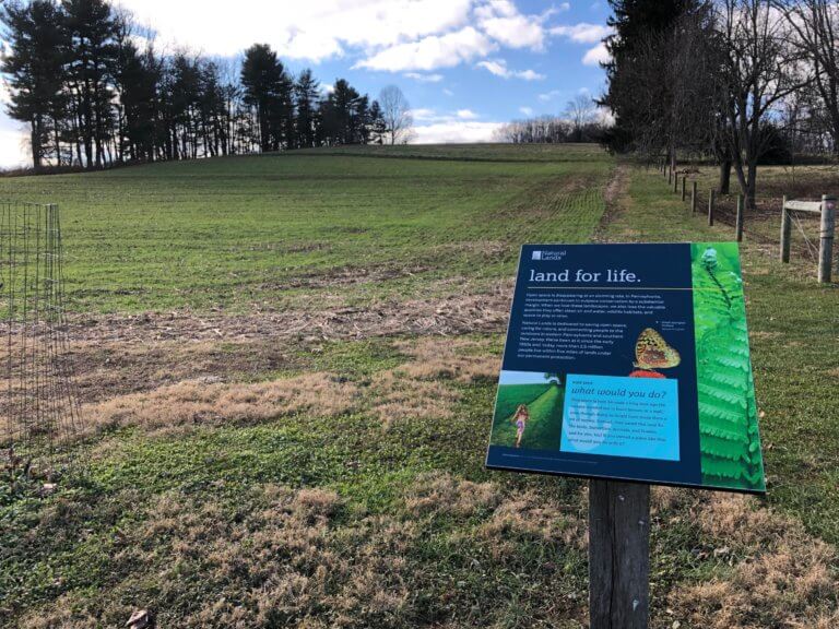 An interpretive sign in front of a field.