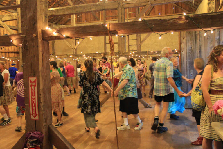 People dance in a wooden barn.
