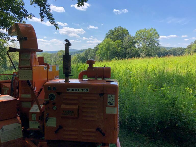 A wood chipper in front of a green meadow.