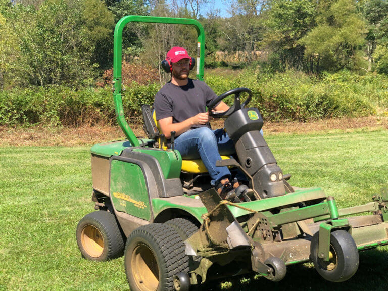 A man drives farm equipment in a natural setting.