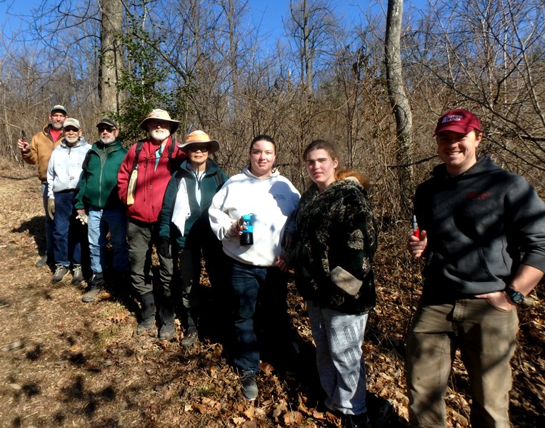 A group of volunteers smile for the camera in a winter forest.