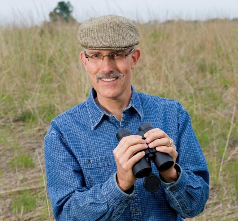 Portrait of smiling man holding binoculars.