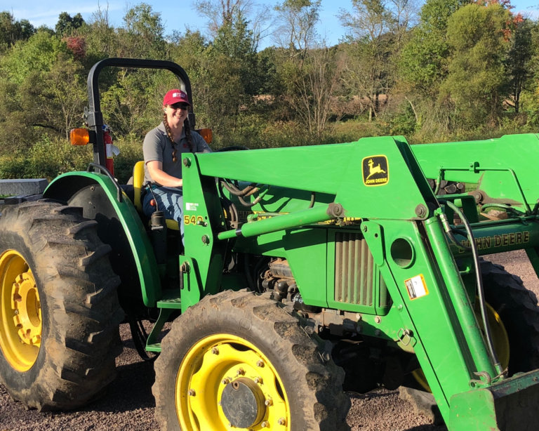 A woman wearing a red hat on a green tractor