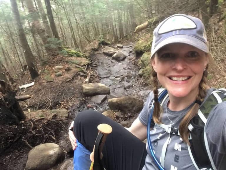 Selfie of a woman with blond hair in the forest along a hiking trail