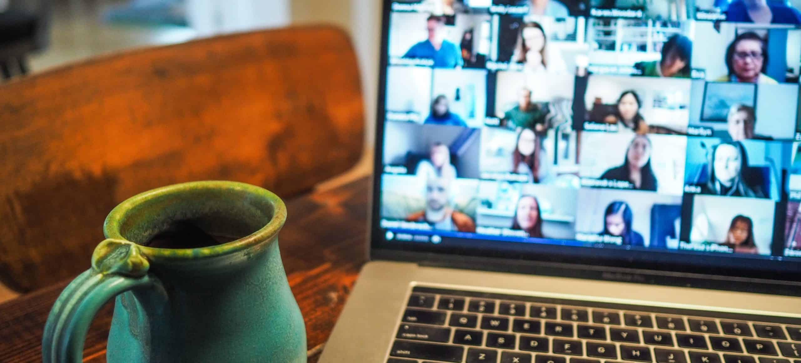 A laptop with a Zoom meeting on the screen and a pottery coffee mug