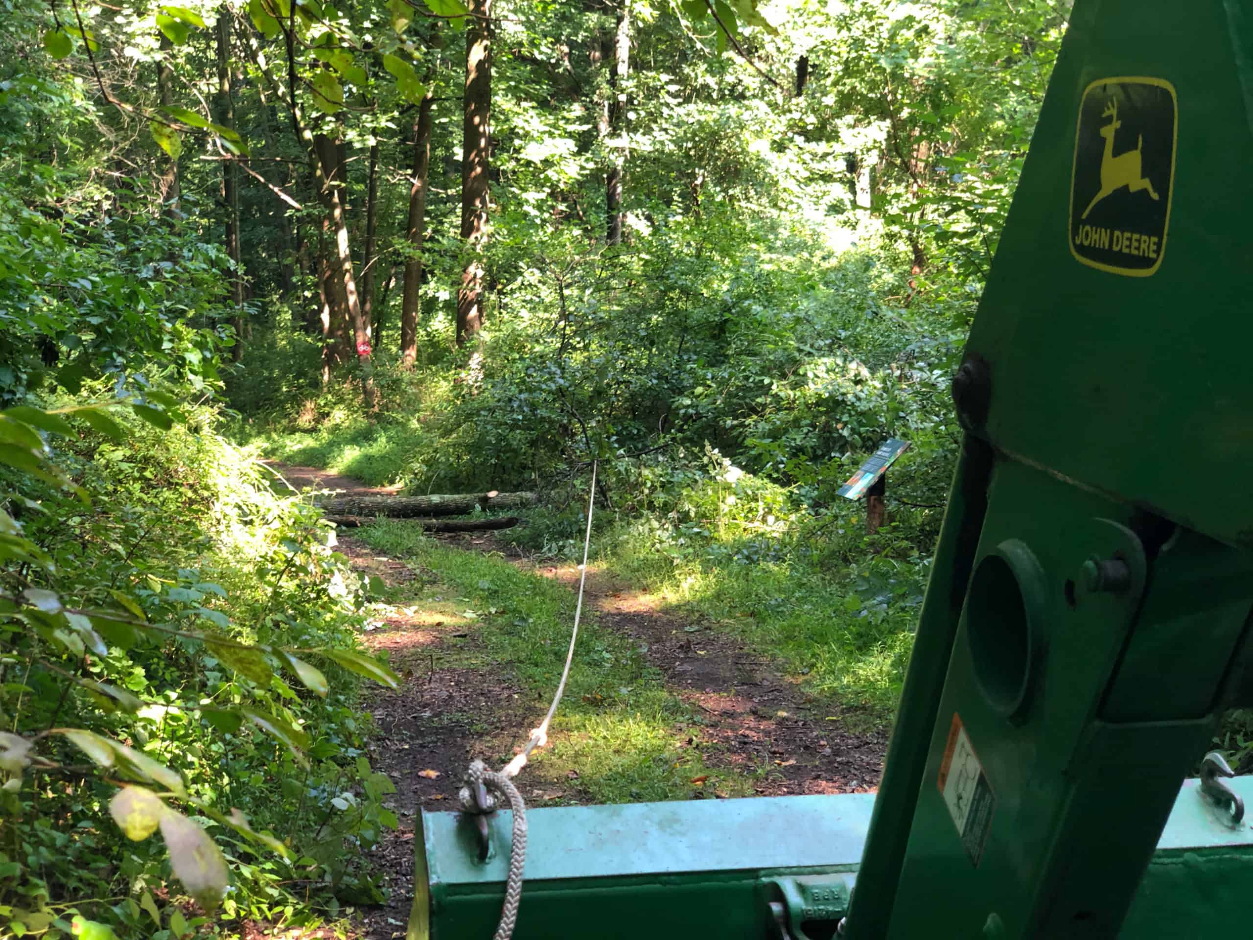 A tractor pulling down a branch that was hanging over a trail