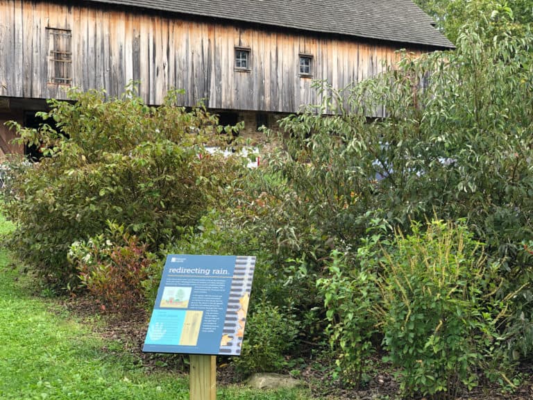 Rain garden and interpretive sign about it at barn