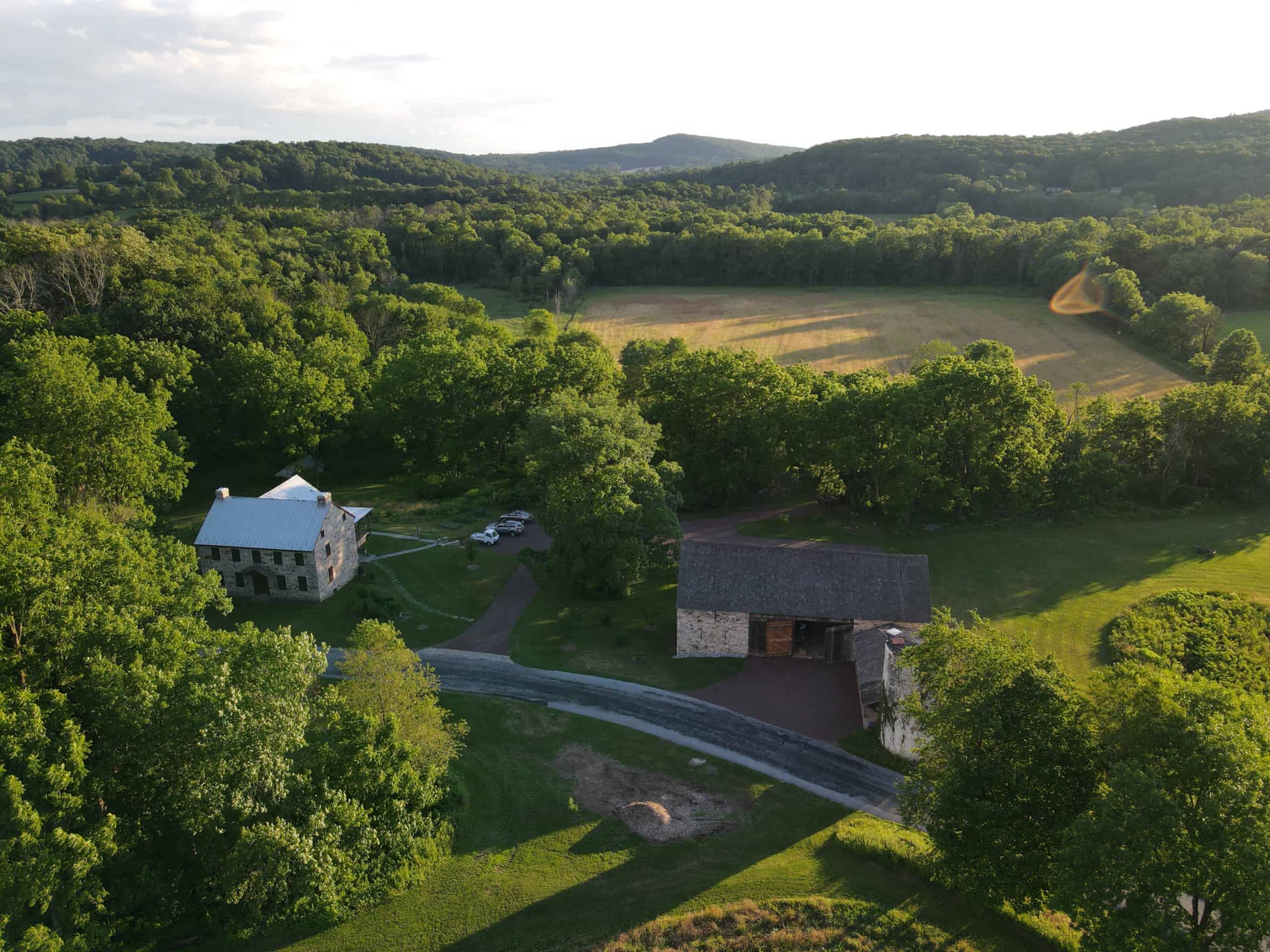 Aerial view of historic house and barn with farm fields and woods