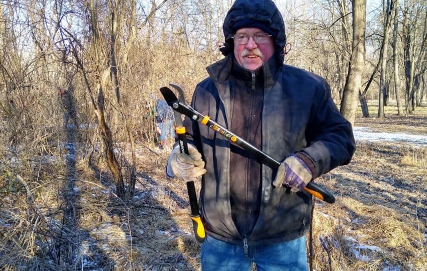 Man holding loppers, standing in woods in winter