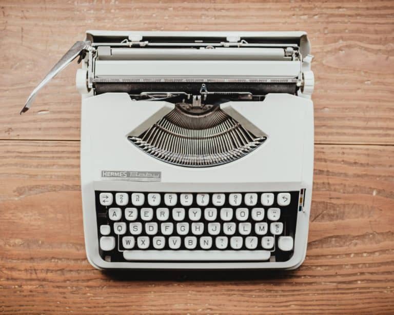 photo of an old-fashioned typewriter on a wooden desk