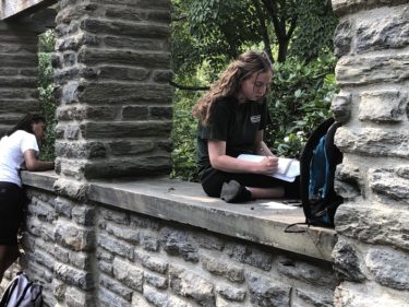 Two students write under the stone pergolia at Stoneleigh