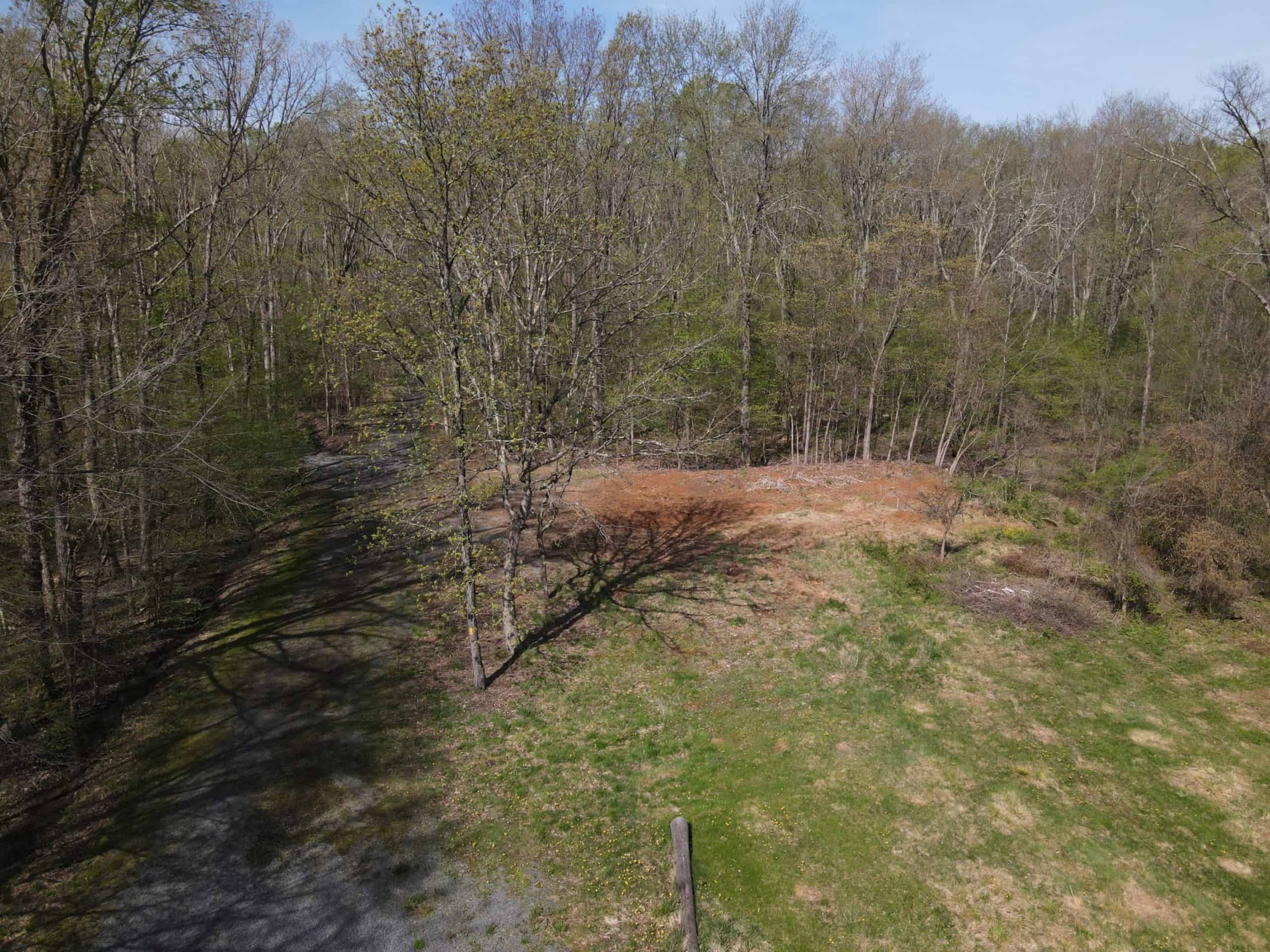 An aerial view of an opening in the woods where a building was removed