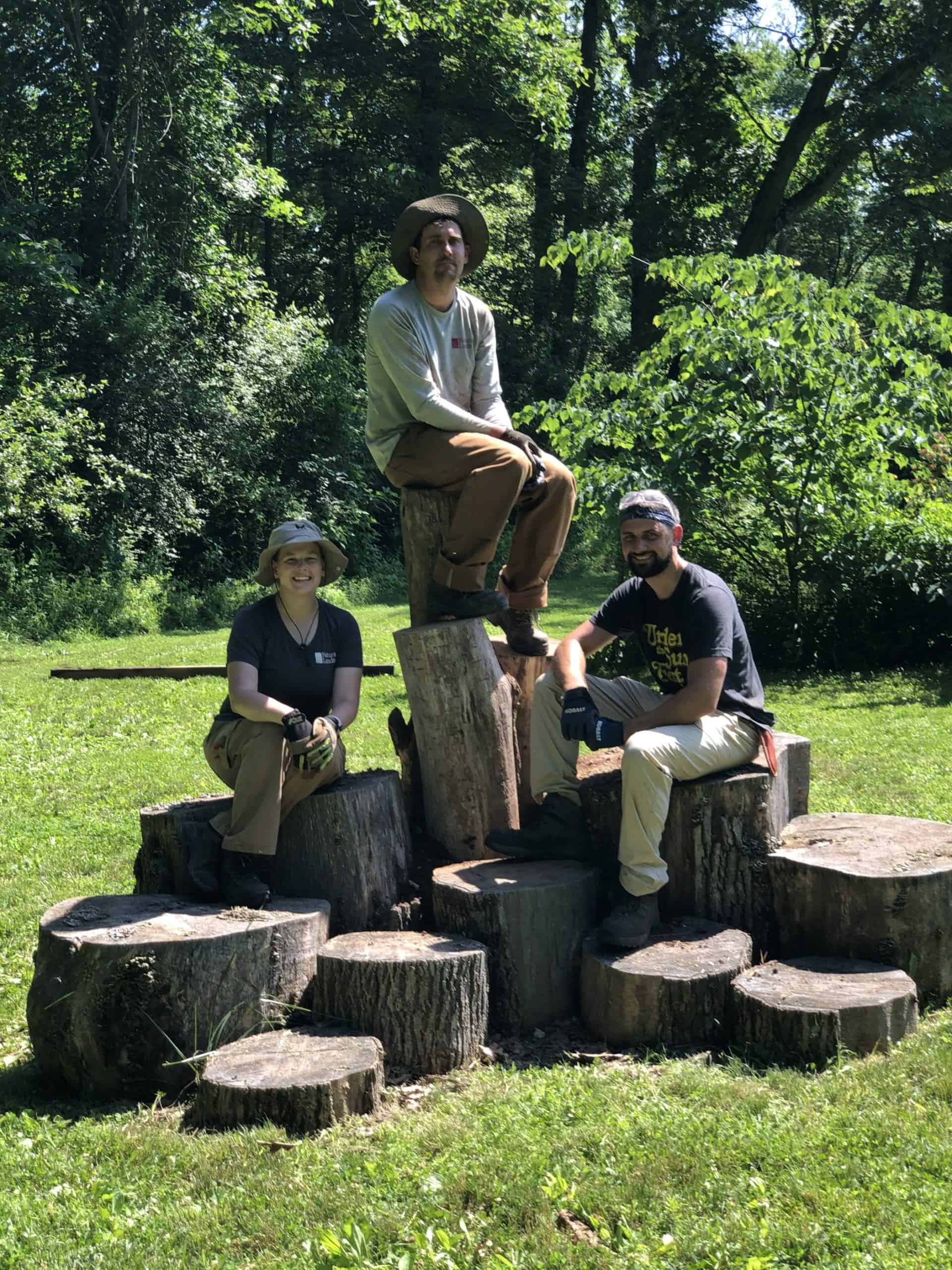 Preserve staff sitting on a climbing structure they built for kids at Crow's Nest Preserve