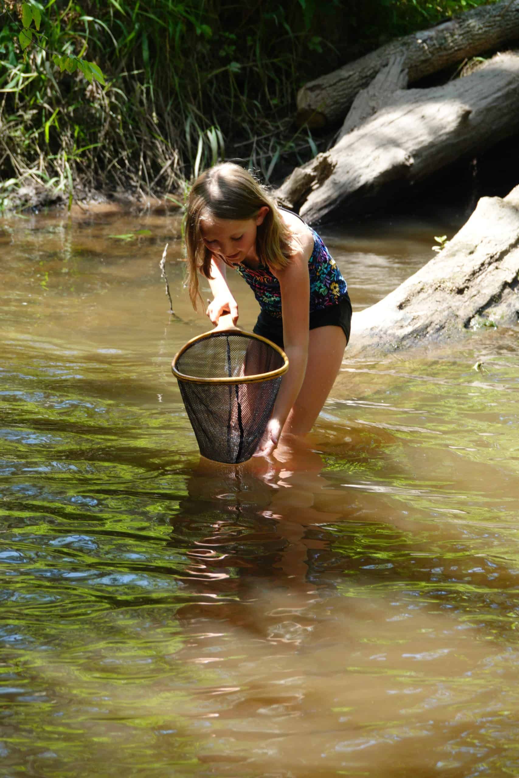 A girl with a net in a stream