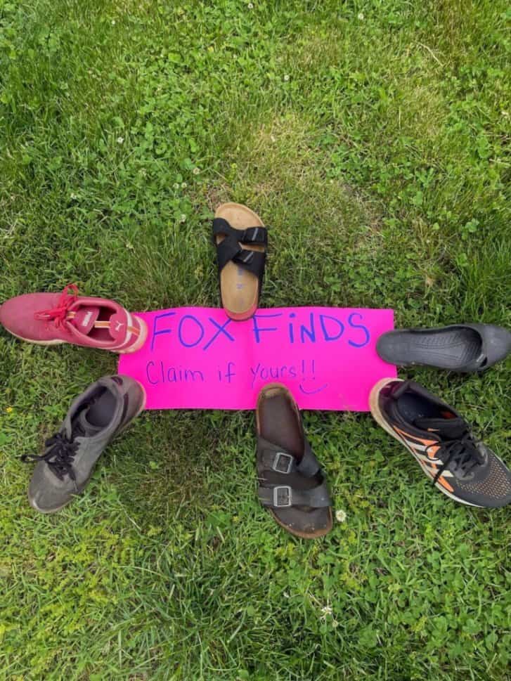 Six shoes on the grass next to a pink sign that says, "Fox finds. Claim if yours."