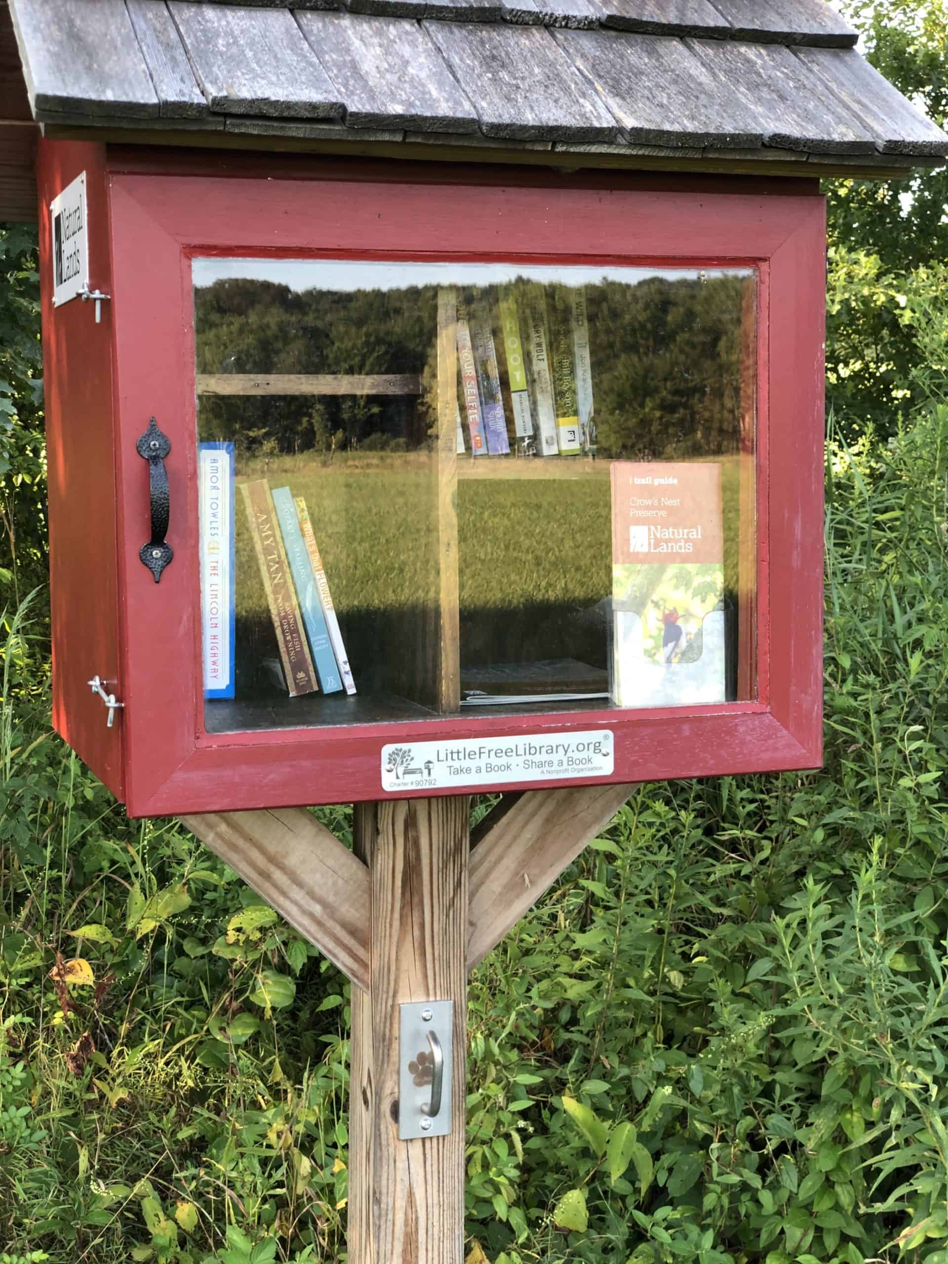 Landscape reflected in the glass door of a tiny library at Crow's Nest Preserve