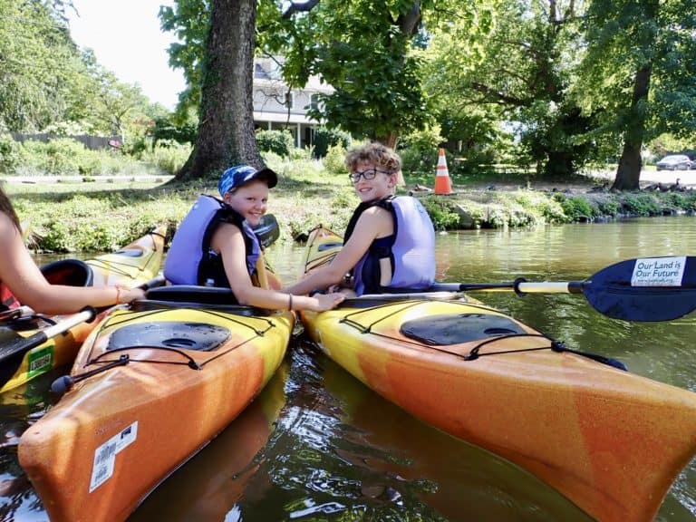 Two kids in kayaks pause in the Schuylkill Canal