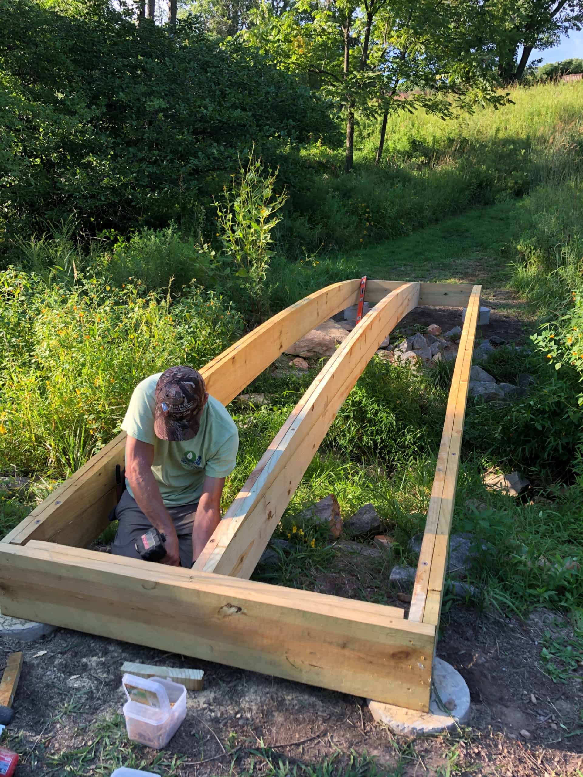 Man preparing joists for arched footbridge installation