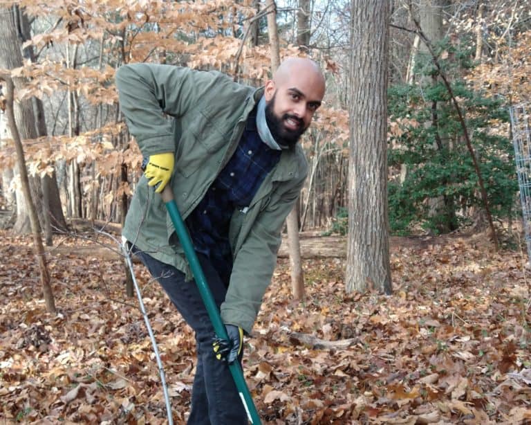 a man volunteer holding shovel while planting a tree in a forest