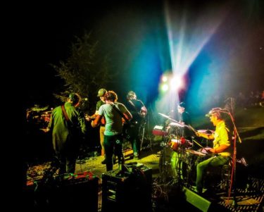 band outdoors spotlighted by a glowing light