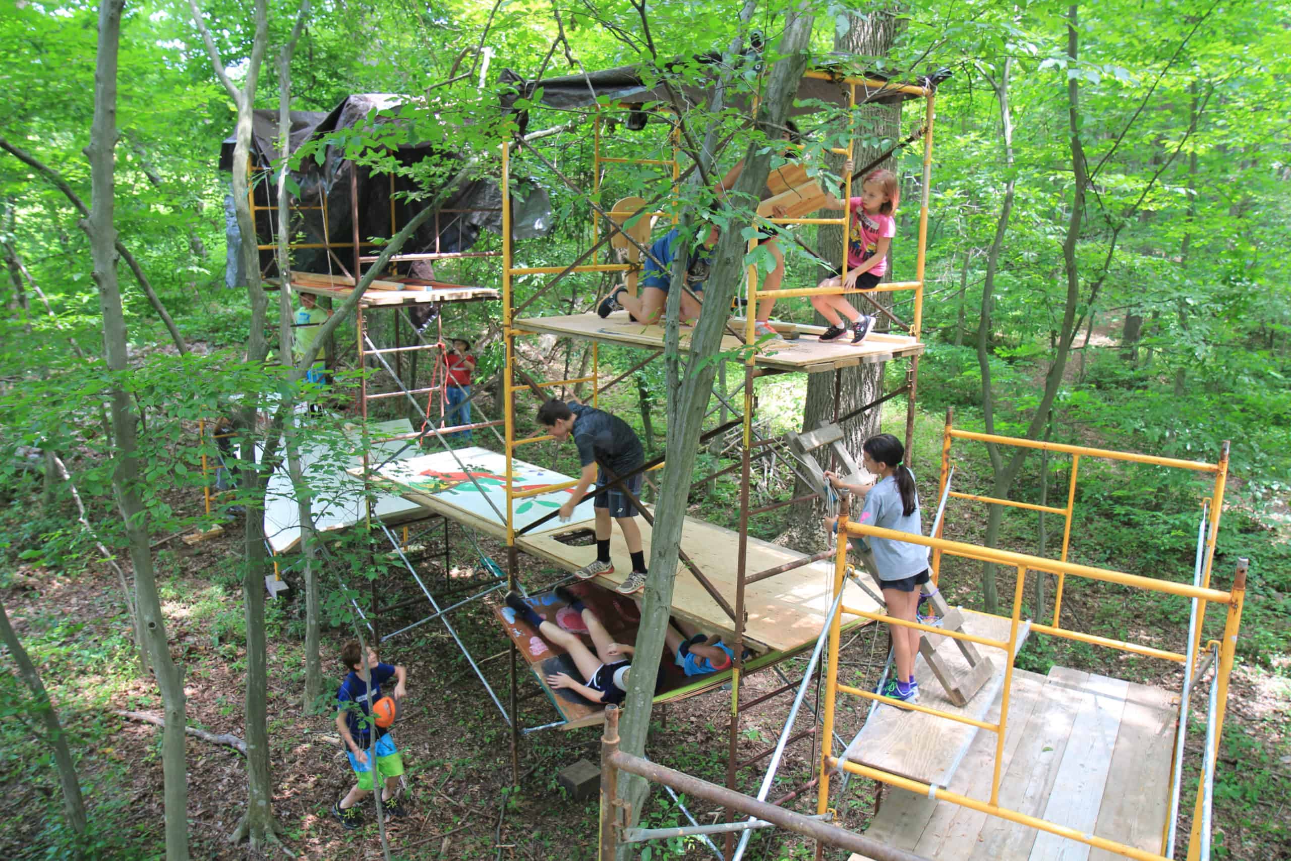 Kids playing on temporary treehouses in the woods at Crow's Nest Preserve.