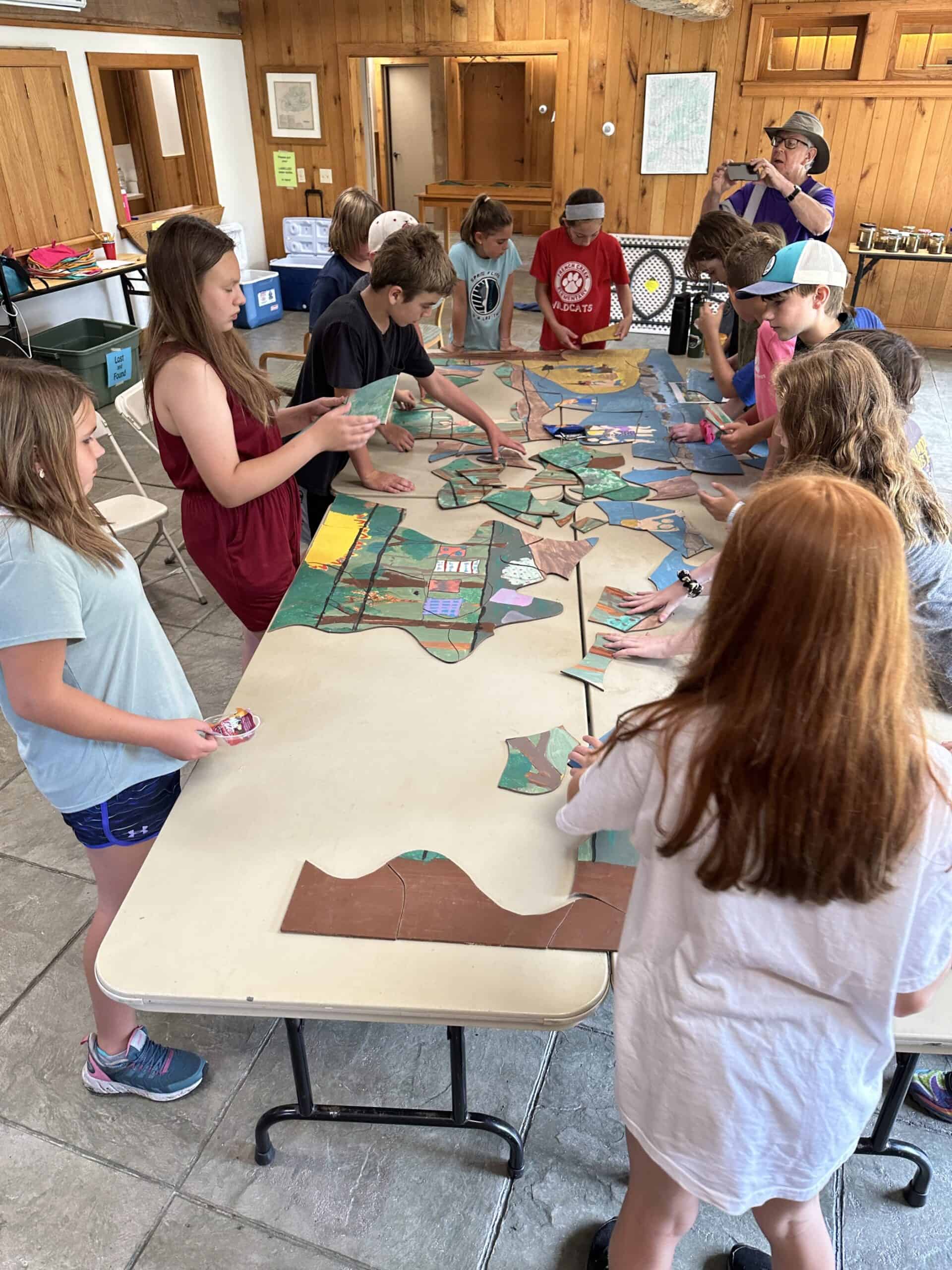 Crow's Nest Camp kids assembling a giant puzzle they had earlier painted before it was cut into pieces