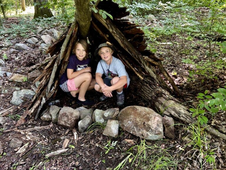 Kids crouched in a woodland shelter