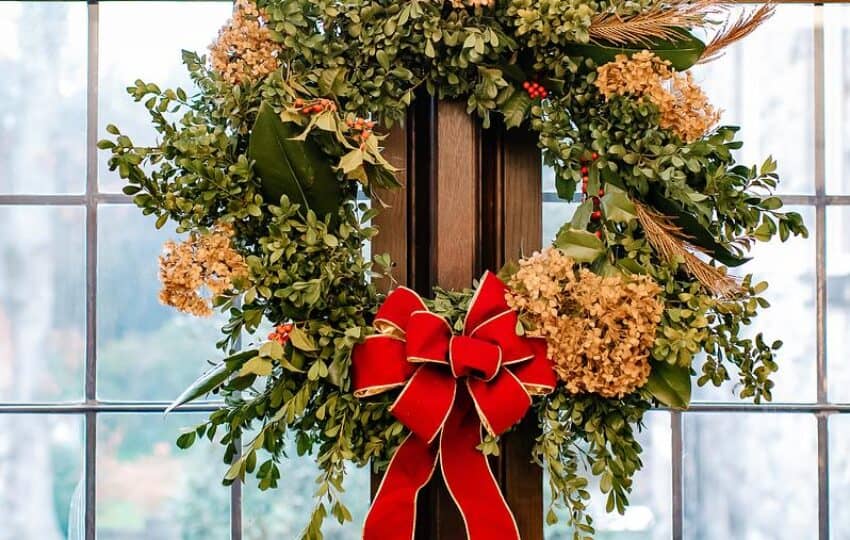 A festive wreath hangs on a glass door.