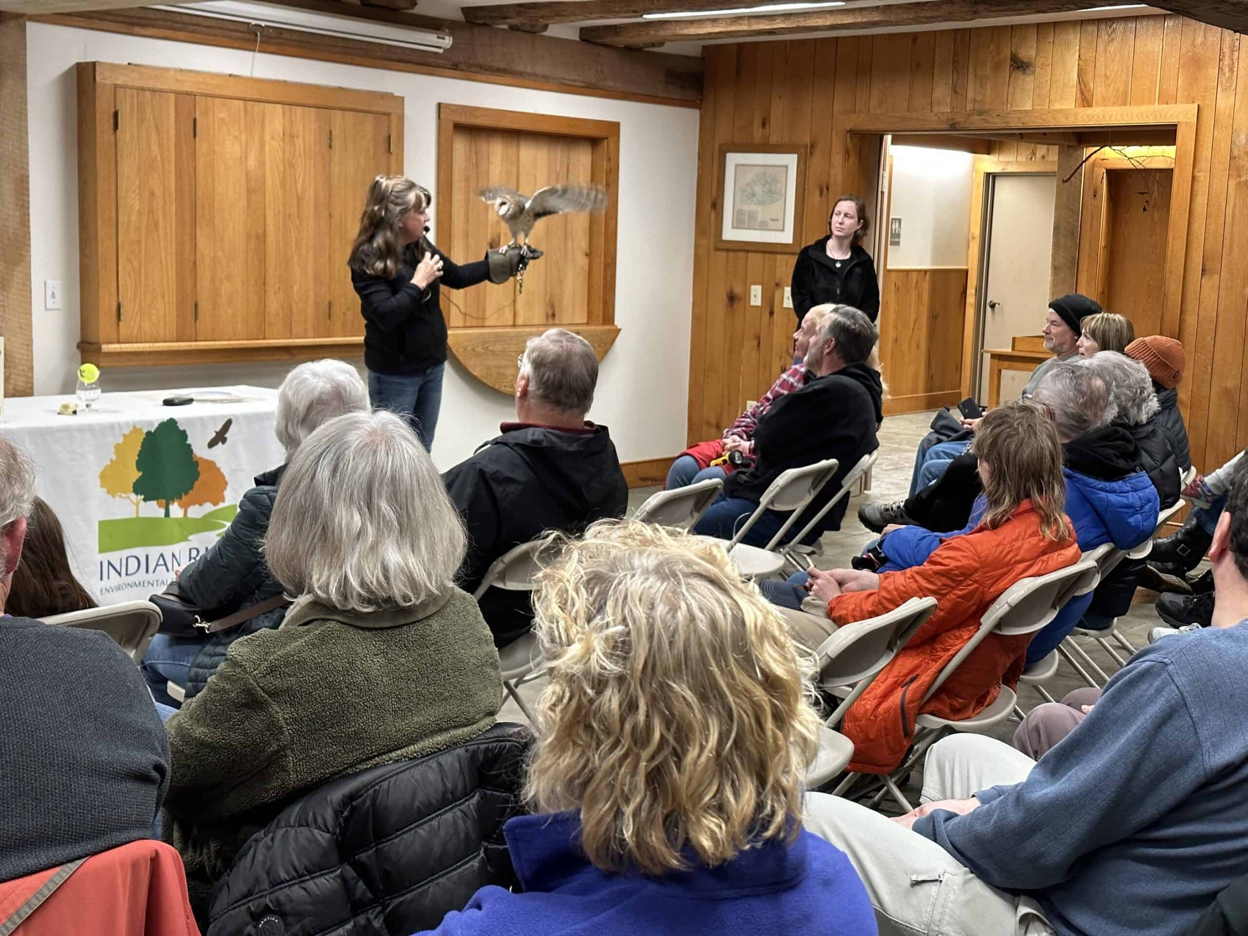 A woman holding and teaching about a barn owl that cannot be released to the wild.