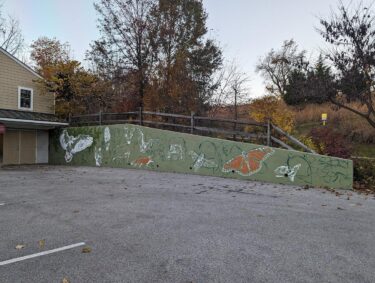An outdoor mural of plants and animals in the parking lot at Binky Lee Preserve
