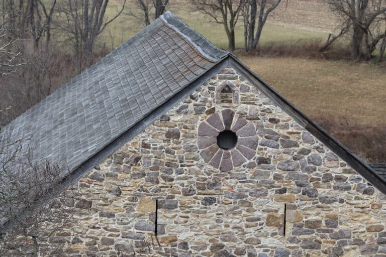 Outside view of historic barn at Crow's Nest Preserve showing masonry wall and wood shingle roof.