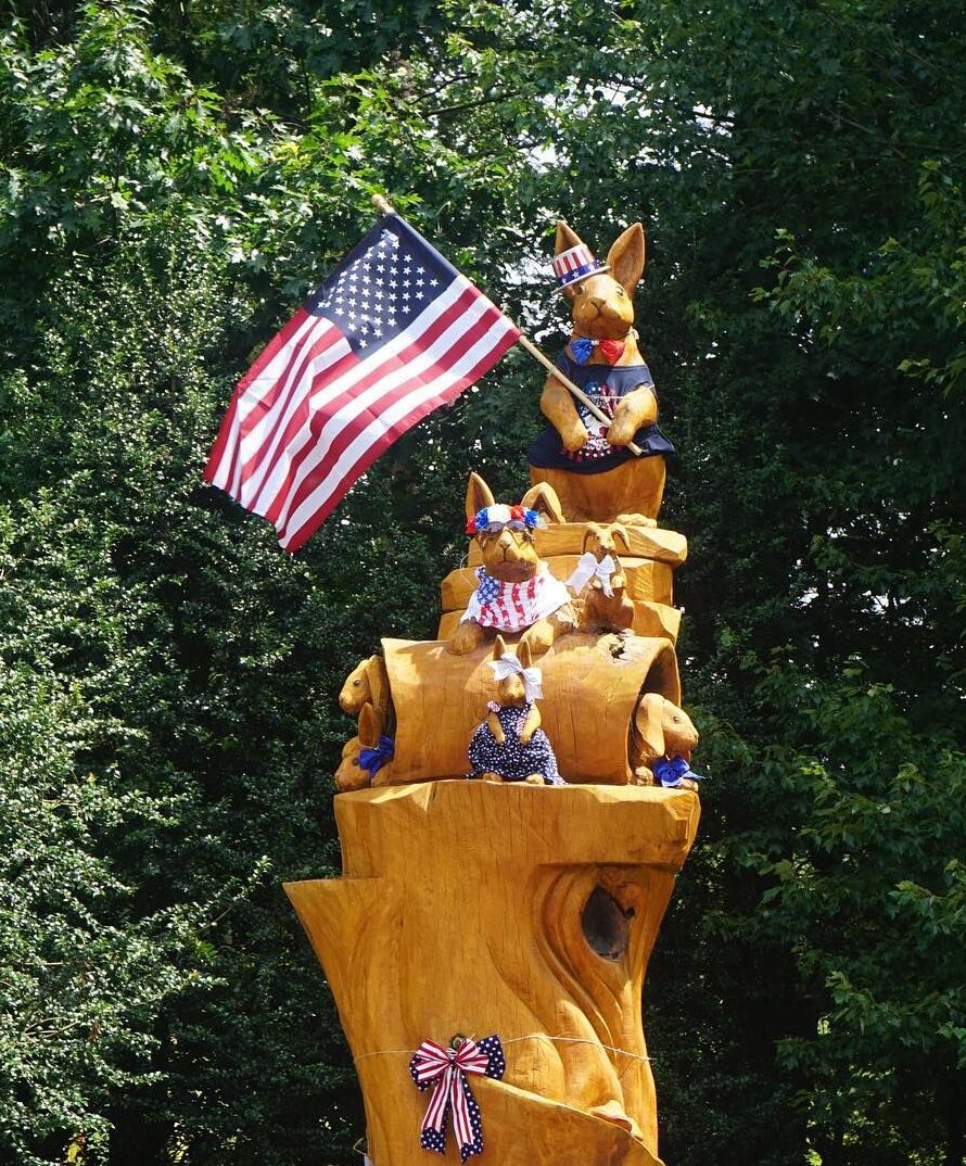 A tree trunk carved into a family of hares is decorated for the Fourth of July holiday.