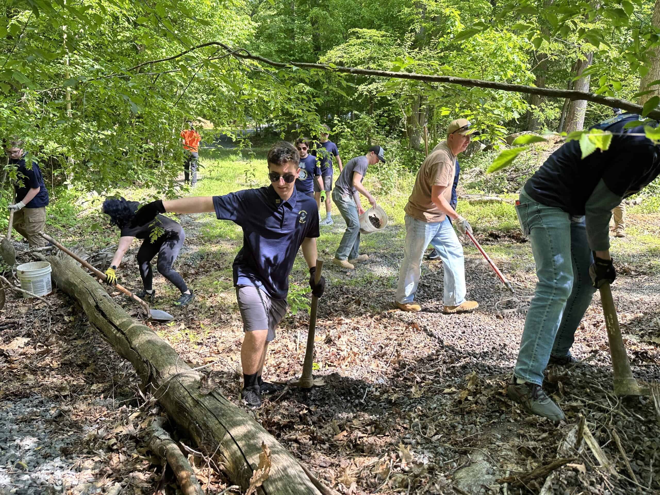Owen J. Roberts JROTC students with rakes and shovels moving gravel in the woods