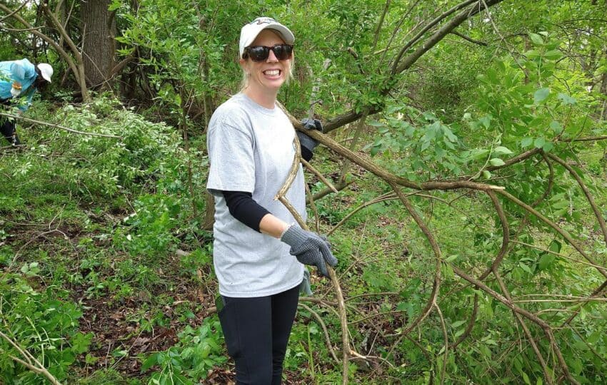 a woman in sunglasses smiling while removing invasives