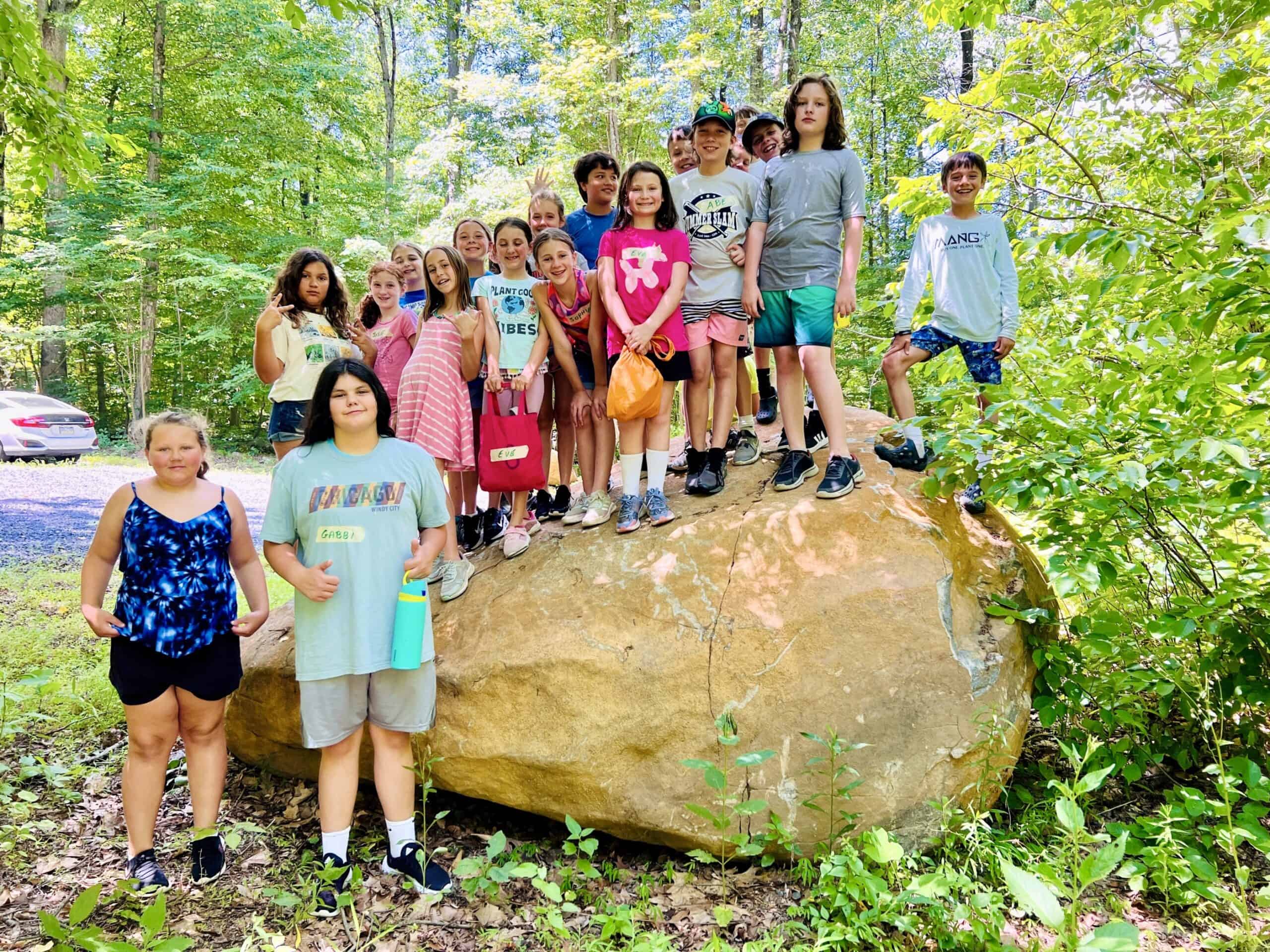 Camp kids posing on a giant rock in the woods