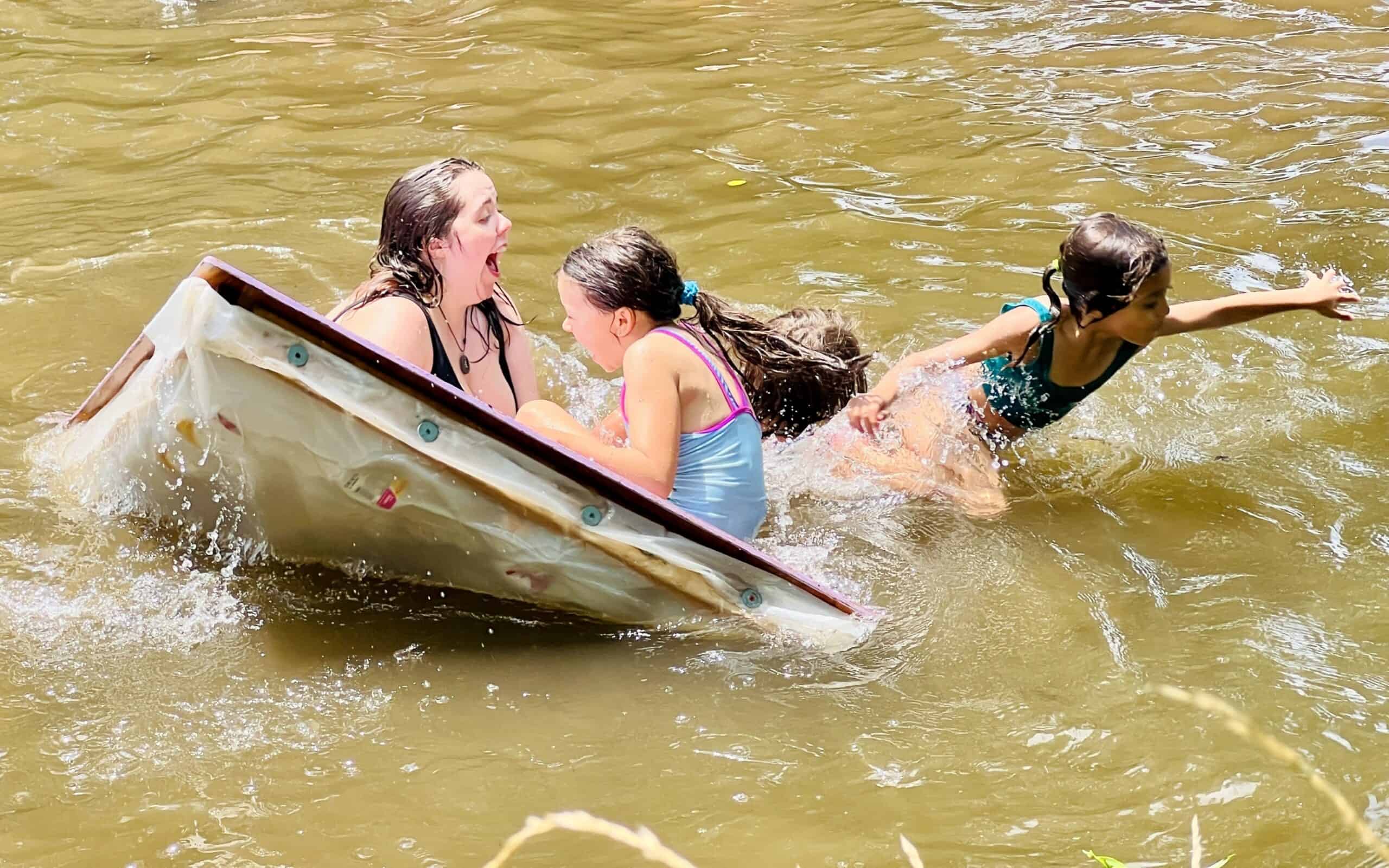 Kids playing on a raft in the creek.