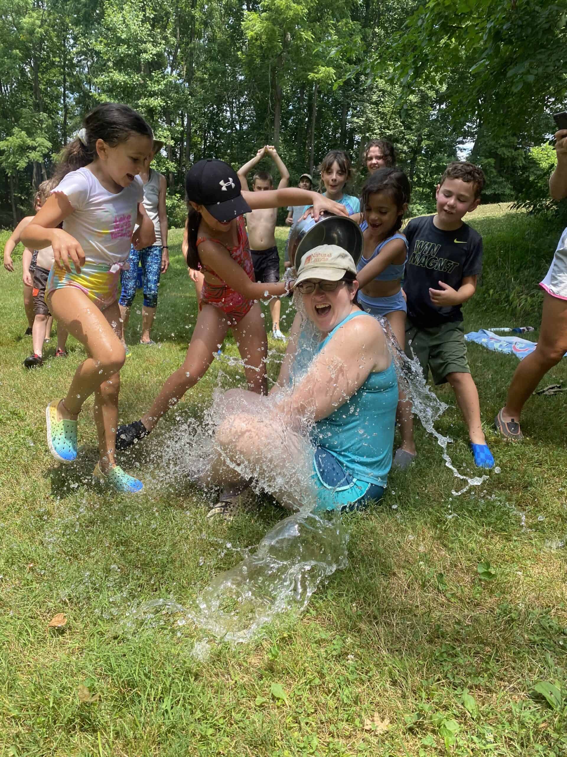 A camp counselor being splashed with water.