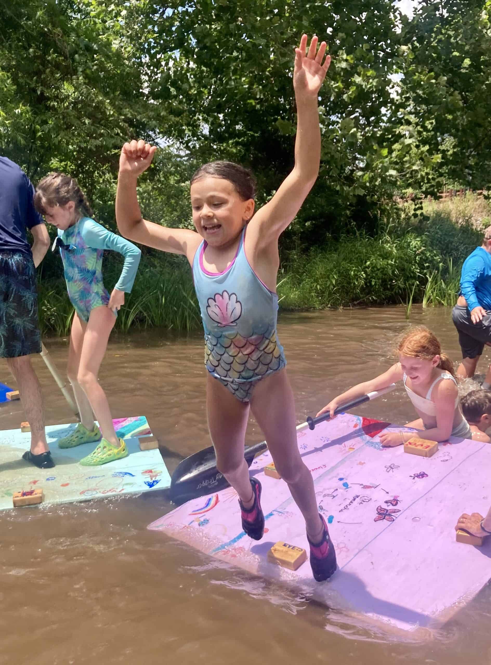 A kid leaping from a raft in the creek.