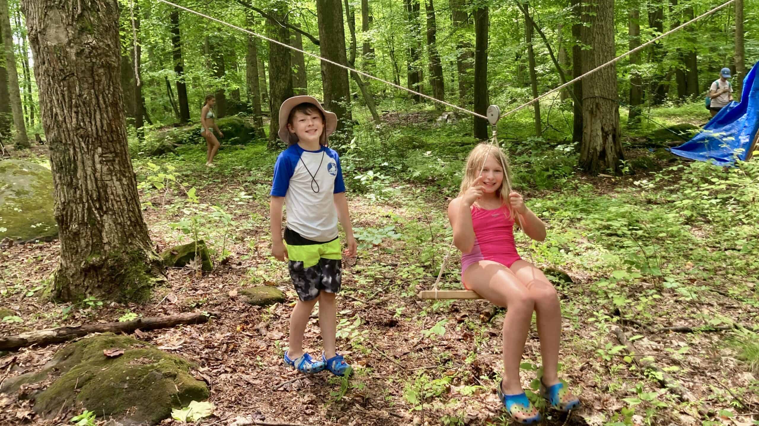 Kids playing on a rope swing in the woods at Crow's Nest Camp