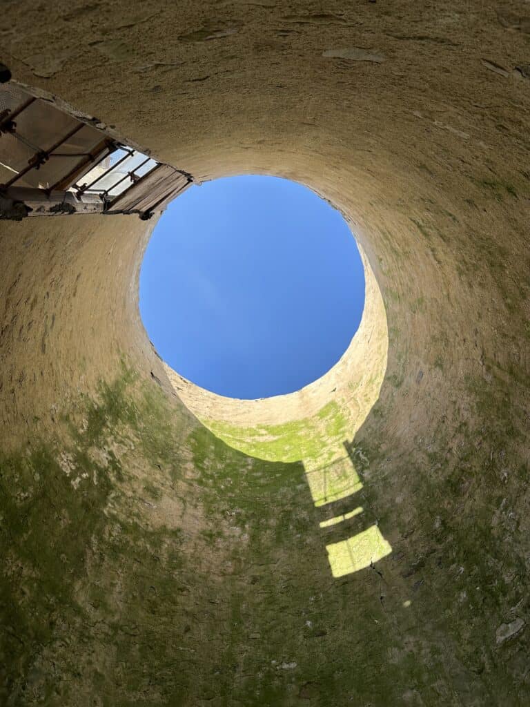 daytime sky showing through a circular opening in a silo that is temporarily without a roof