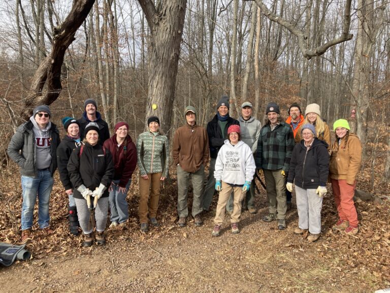 Volunteers posing at the edge of the woods following a workday.